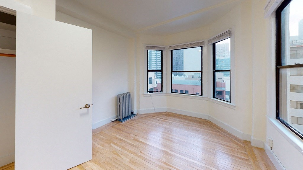 an empty living room with a radiator and a window