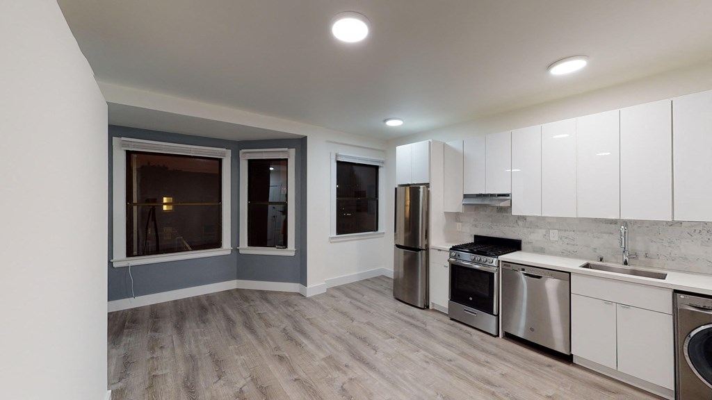 Kitchen with multiple cabinets, refrigerator, stove, range hood, and sink