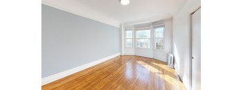 an empty living room with wood floors and a window