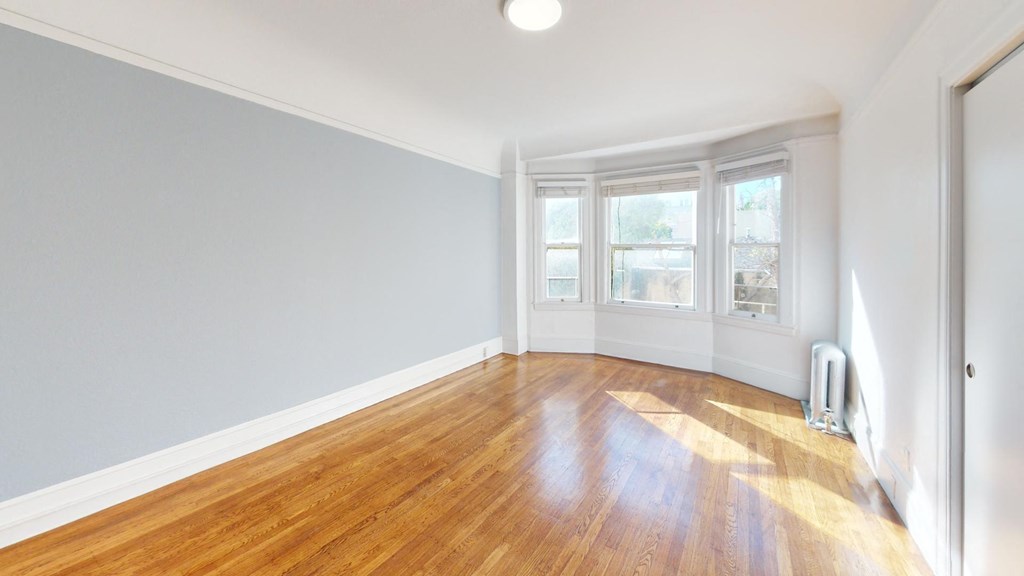 an empty living room with wood floors and a window