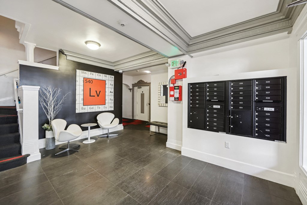 Apartment lobby with staircase, armchairs, and mailboxes