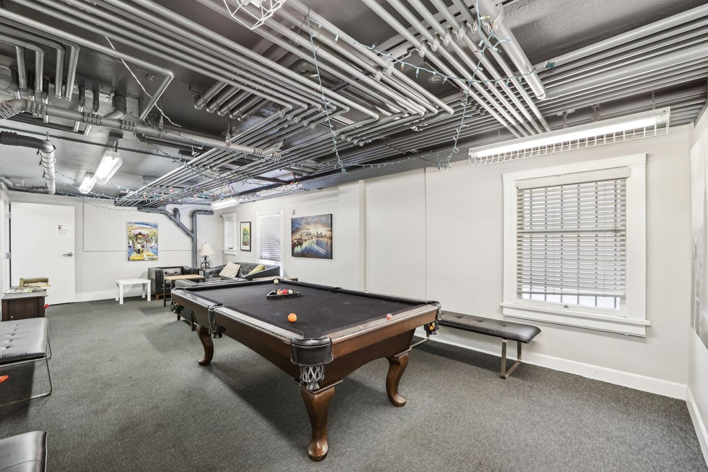 Basement room with pool table surrounded by a couch and a bench