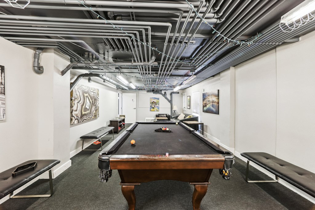 Basement room with pool table surrounded by a couch and a bench