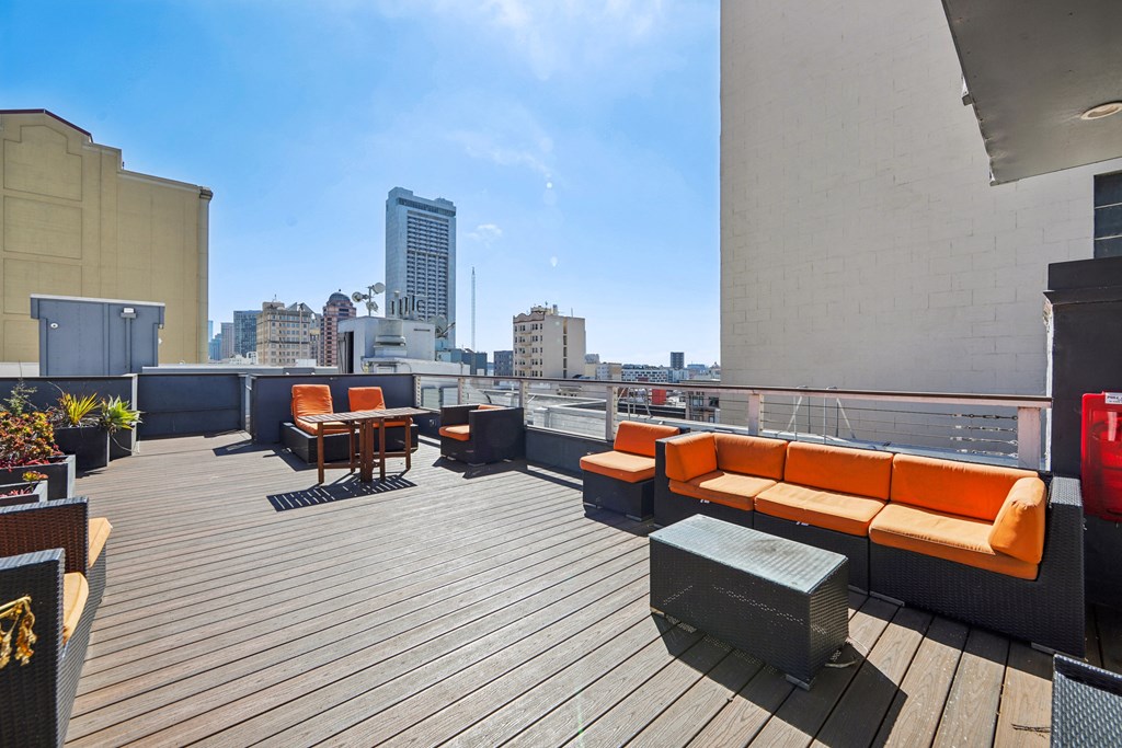 Rooftop patio with lounge chairs, potted plants, and table