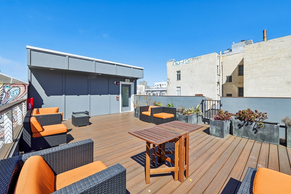 Rooftop patio with lounge chairs, potted plants, and table