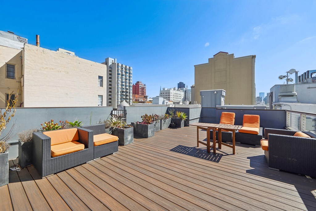 Rooftop patio with lounge chairs, potted plants, and table