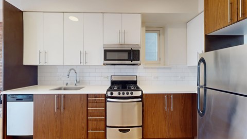 A kitchen with white cabinets and a stainless steel refrigerator.