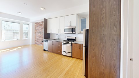 A kitchen with wooden floors and a brick wall.