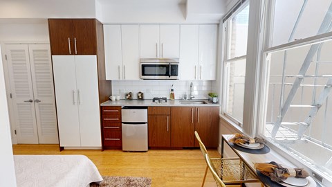 A kitchen with white cabinets and a wooden floor.