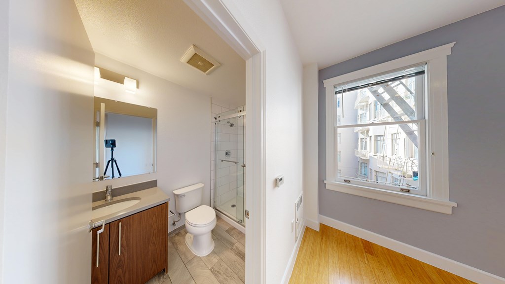 A bathroom with a toilet, sink, and a window.