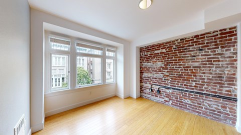 A room with a large window and a brick wall.
