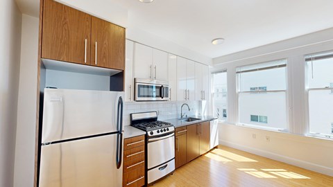 A kitchen with a refrigerator, microwave, oven, and sink.