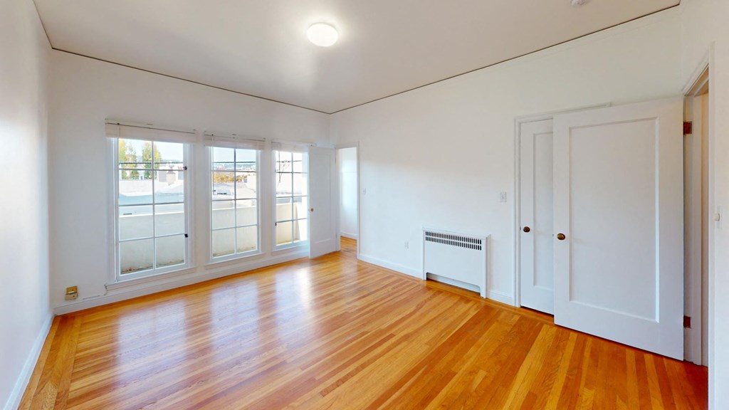 a living room with white walls and wood floors and a white door