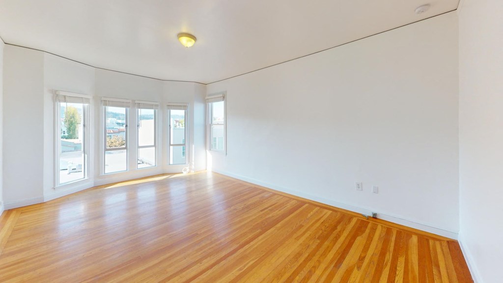 an empty living room with wood floors and white walls