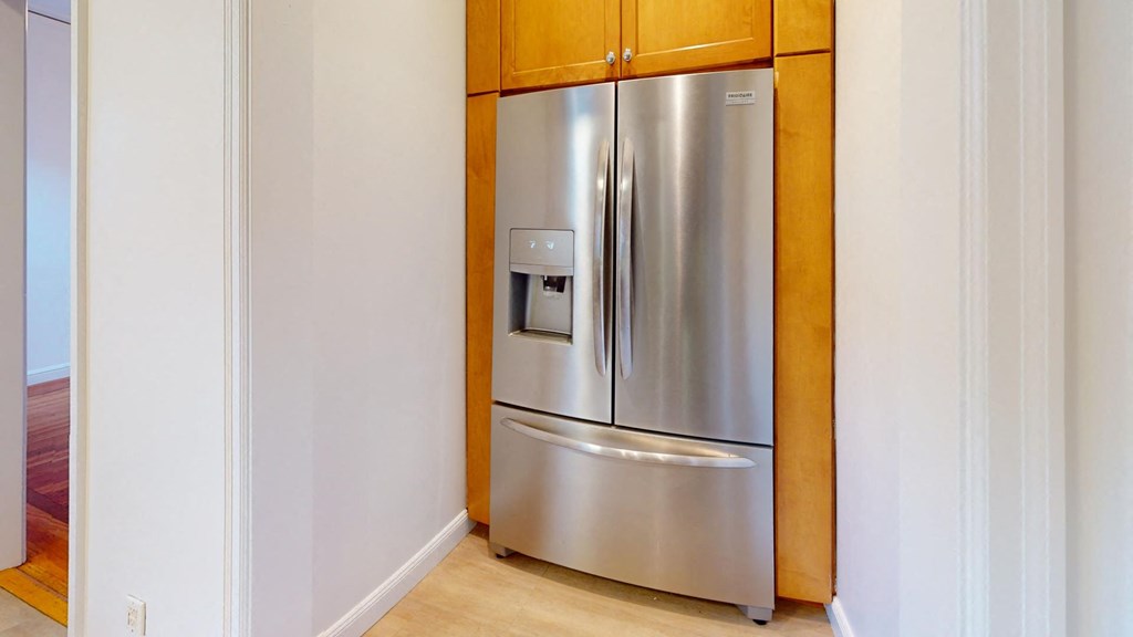 a stainless steel refrigerator in a kitchen with wooden cabinets