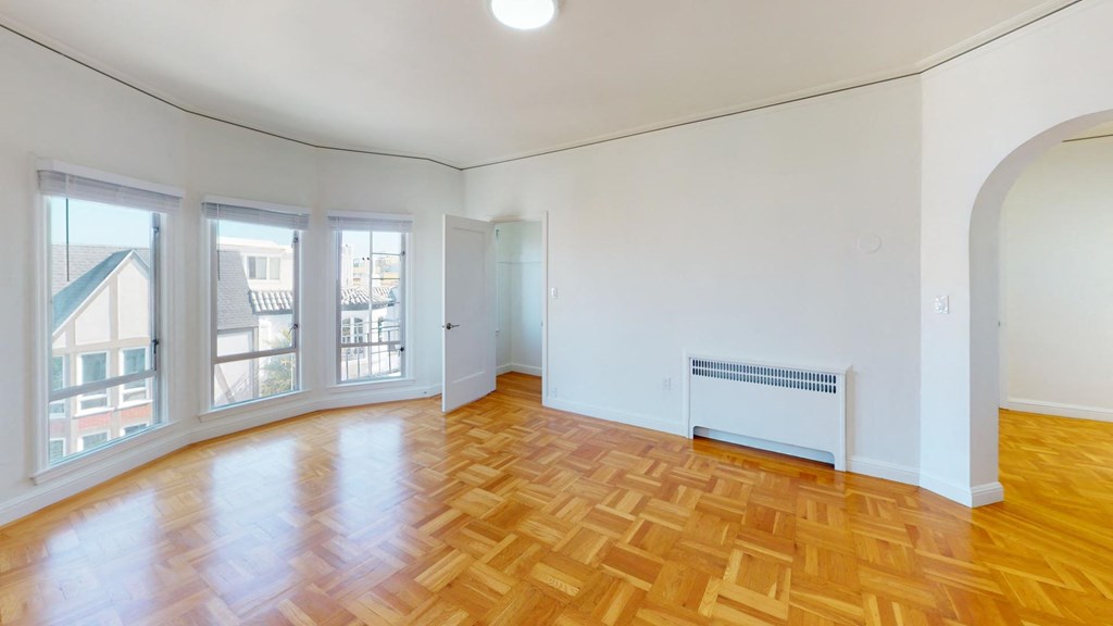 Sunlit room with a large window and a wood-like flooring Sunlit room with a large window and a wood-like flooring