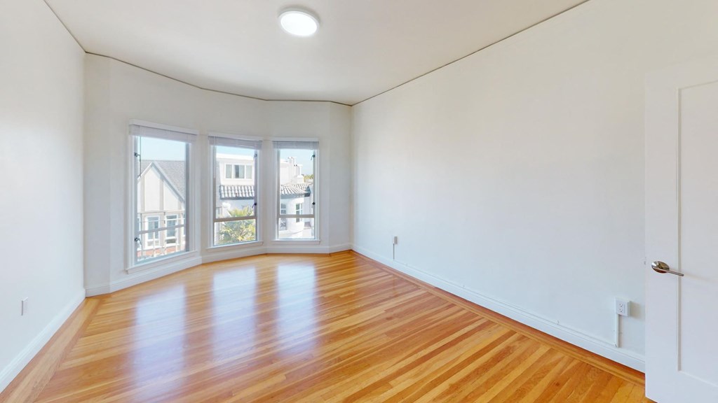 Sunlit bedroom with a large window and a wood-like flooring Sunlit bedroom with a large window and a wood-like flooring