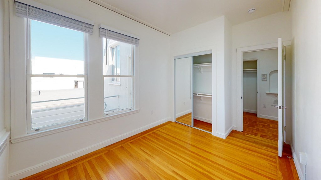 Bright bedroom with wood-like floor and a closet with mirror Bright bedroom with wood-like floor and a closet with mirror