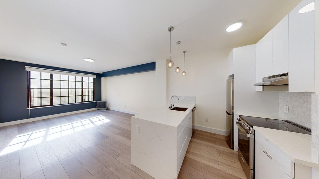 an empty kitchen with white cabinets and a large window