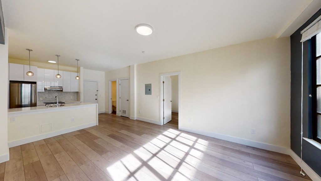 an empty living room and kitchen with white walls and wood floors