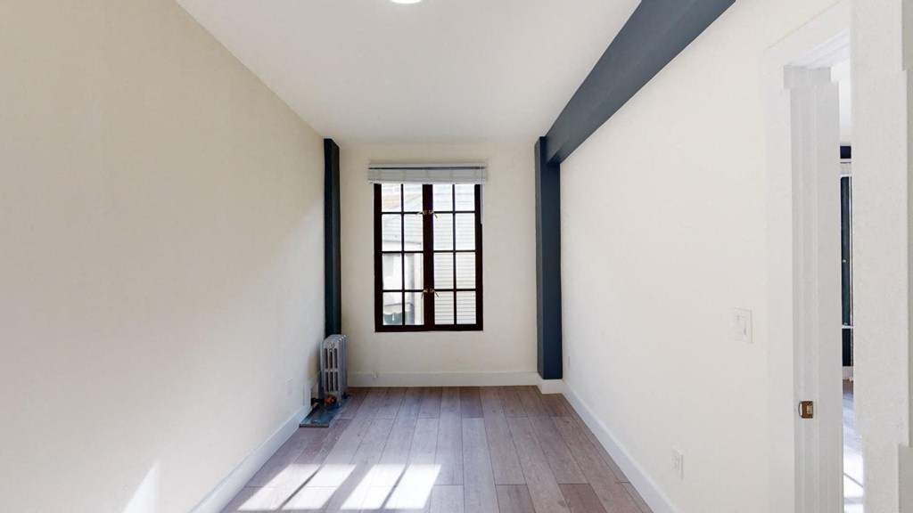 a living room with white walls and a window and wooden floors