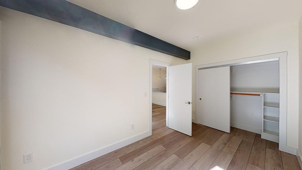 a bedroom with a closet and a hard wood floor