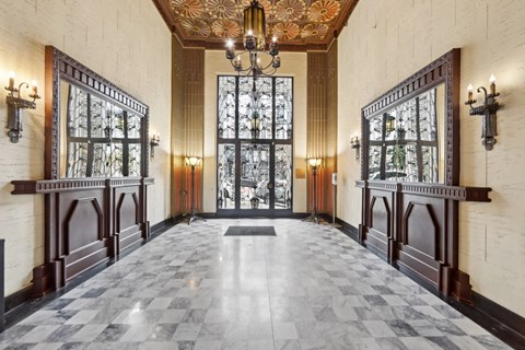 Grand entrance to a building, featuring a large, ornate chandelier suspended from the ceiling, casting a warm glow over the space
