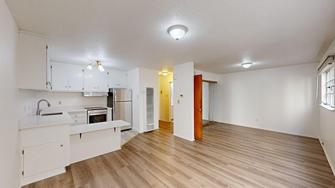 A kitchen with white cabinets and a wooden floor.