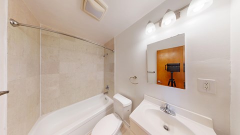 A bathroom with a white tub, toilet, and sink.