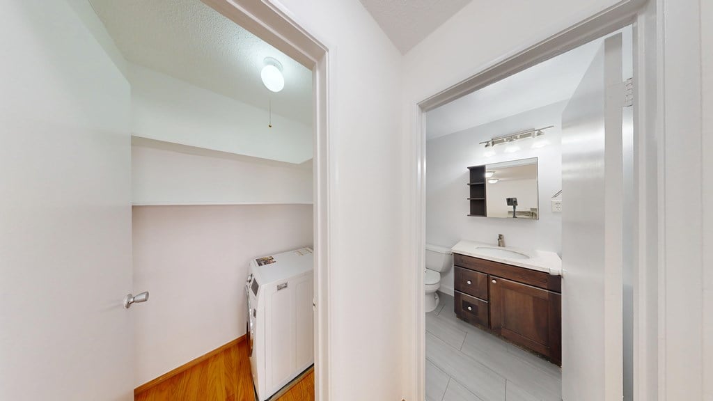 A white bathroom with a toilet, sink, and mirror.