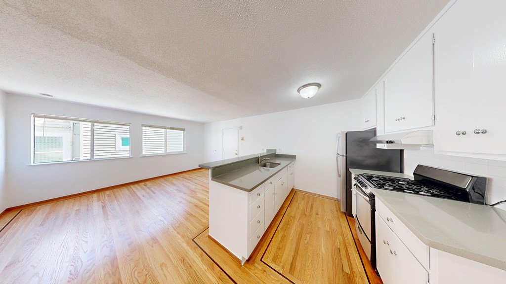 A kitchen with white cabinets and wooden floors.