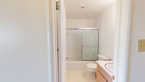A white bathroom with a toilet, sink and shower.