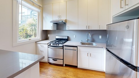 A modern kitchen with white cabinets and stainless steel appliances.