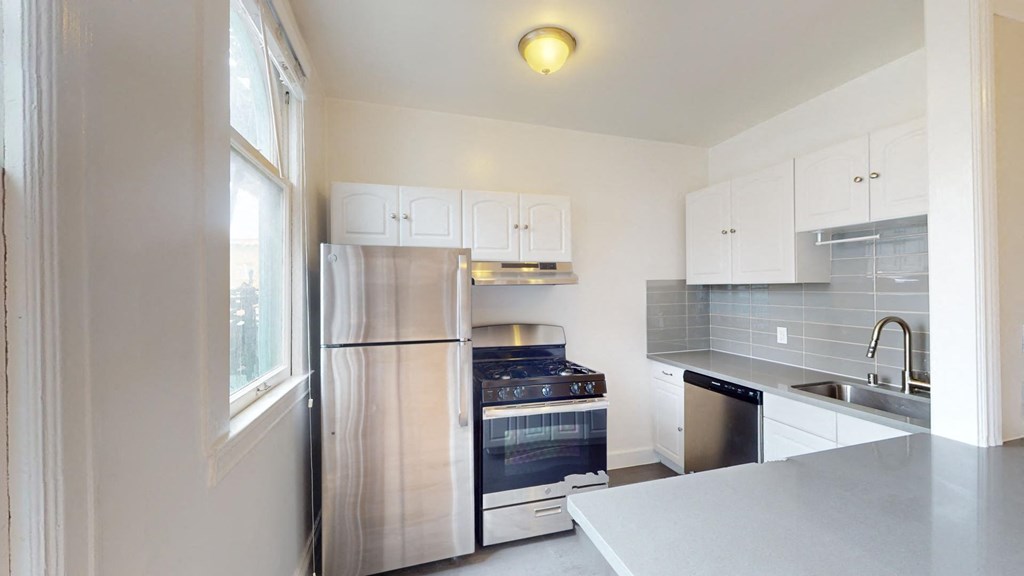 Kitchen with multiple cabinets, refrigerator, stove, range hood, and sink
