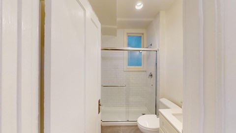 A white bathroom with a toilet, sink, and shower.