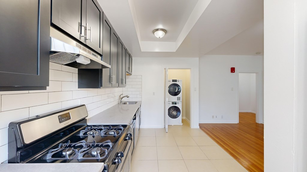 A modern kitchen with a stainless steel stove and black cabinets.