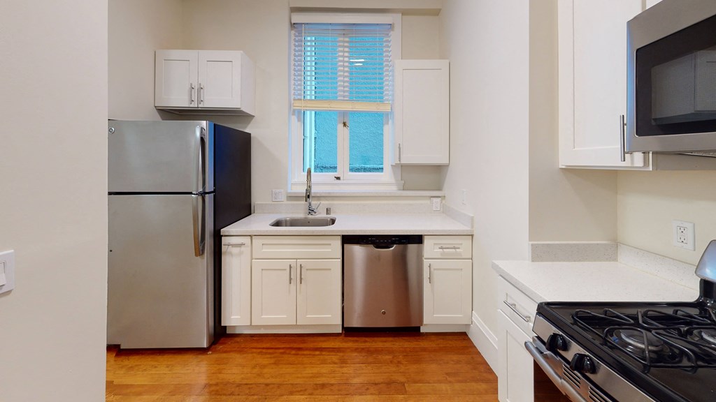 a kitchen with white cabinets and stainless steel appliances and a window