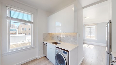 A modern kitchen with a washing machine built into the cabinetry.