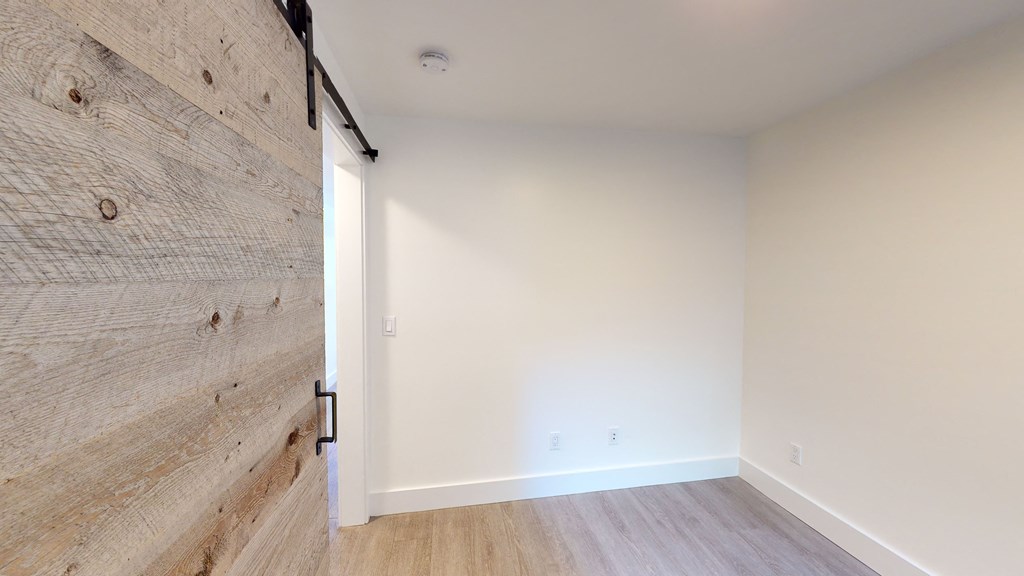 a bedroom with a wood wall and white walls and a door