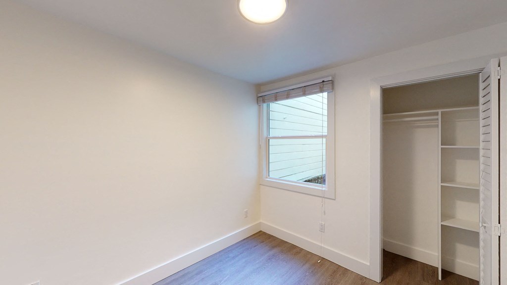 a bedroom with white walls and a window and a closet