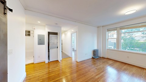 A spacious room with wooden floors and white walls.