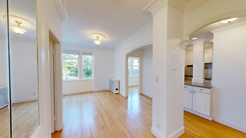 A spacious room with wooden floors and white walls.