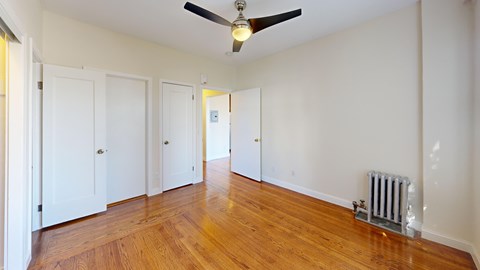 A room with a ceiling fan and a radiator on the floor.