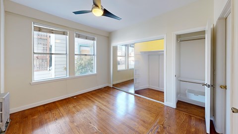 A room with a ceiling fan and wooden floors.