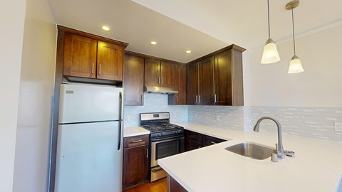 A kitchen with a white counter top and wooden cabinets.