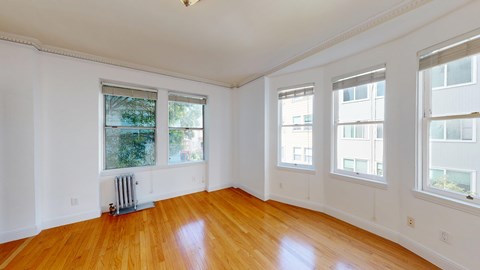 A room with wooden floors and three windows.