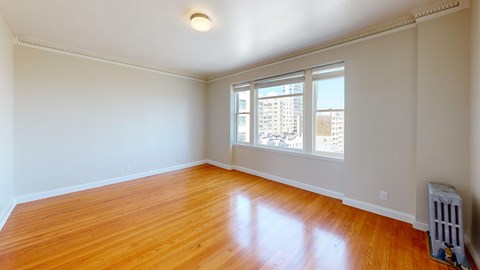 A room with wooden floors and a window overlooking a cityscape.