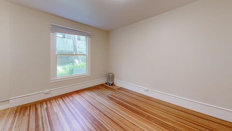 A room with wooden flooring and a window.