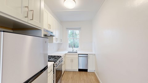 A kitchen with white cabinets and a stainless steel refrigerator.