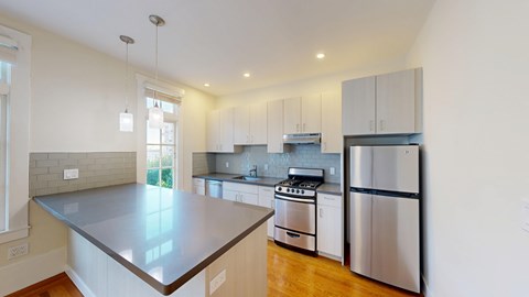 A modern kitchen with stainless steel appliances and wooden floors.